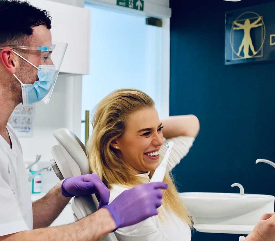 A patient laughing with her dentist who is holding a tooth brush